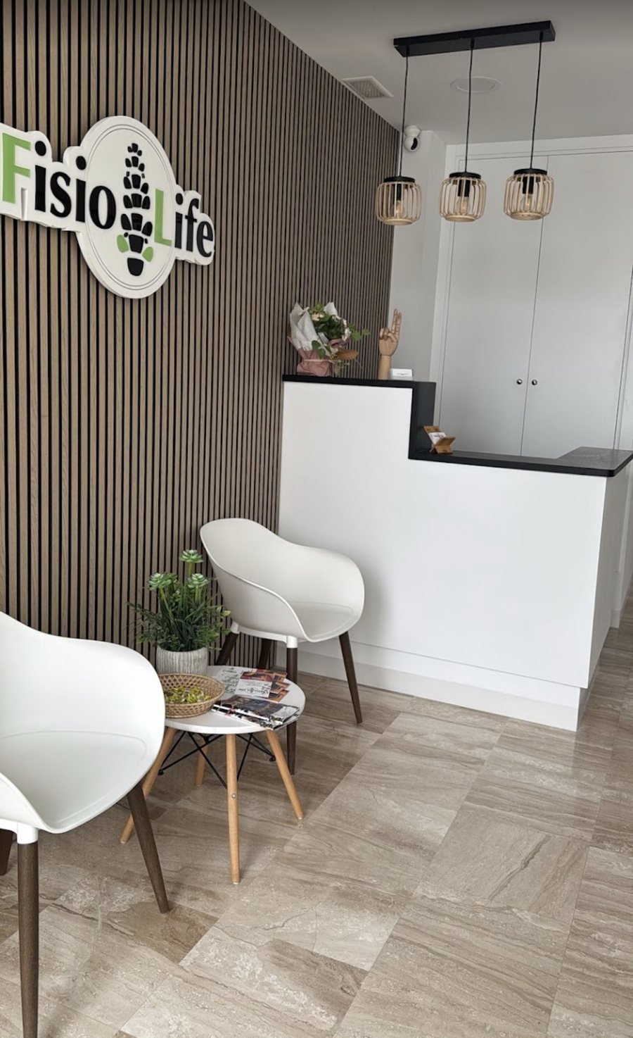 Recepción de FisioLife Conil, con el logo en la pared y zona de espera